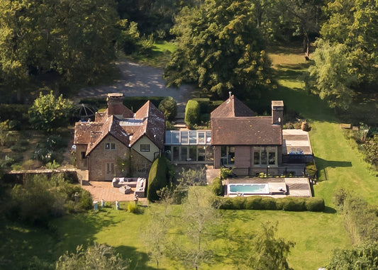 Aerial view of a large house with a pool surrounded by greenery